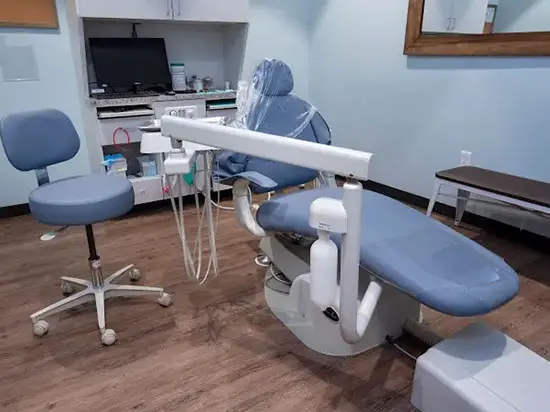 A dentist 's office with blue chairs and a computer.